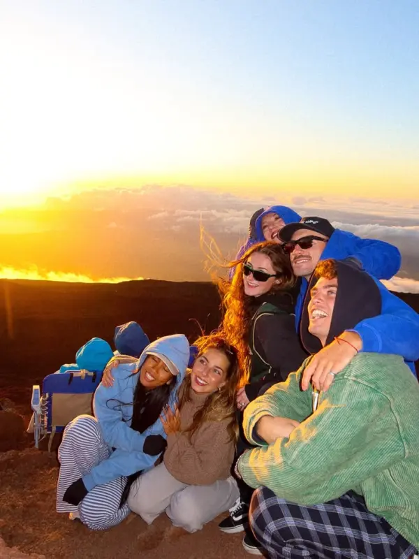 Grupo de amigos viendo el atardecer desde una cumbre en un viaje en grupo